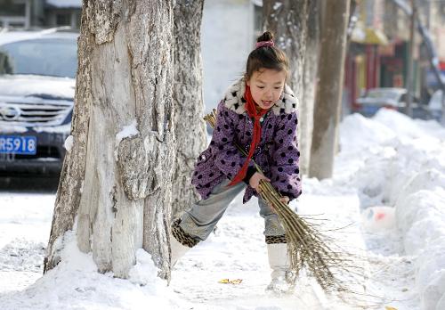 1月19日,乌鲁木齐小朋友刘美彤在扫雪新华社发